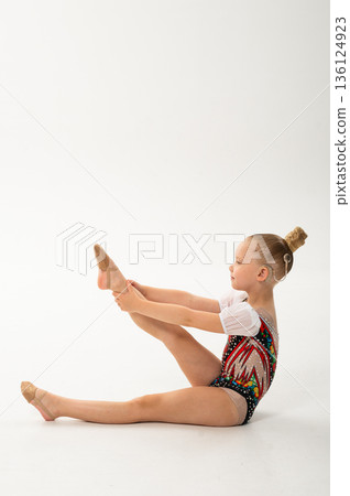 Child rhythmic gymnast with cochlear implant performing leg extension exercise. Hearing loss treatment, cochlear implant rehabilitation, inclusive physical education, balance training, and motor 136124923