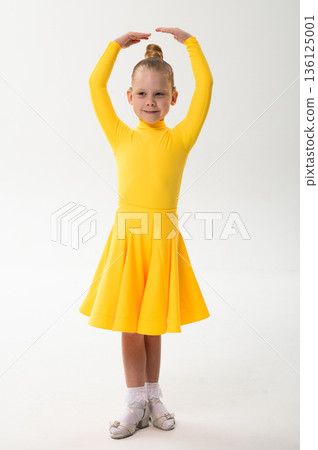 Young girl with cochlear implant performing sport dance in yellow costume on studio background. Hearing loss treatment, auditory rehabilitation, assistive technology, inclusive childhood, and 136125001