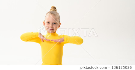 Young girl with cochlear implant performing dance pose in studio. Copy space. Hearing impairment rehabilitation, auditory therapy, assistive hearing technology, inclusive childhood development, and 136125026