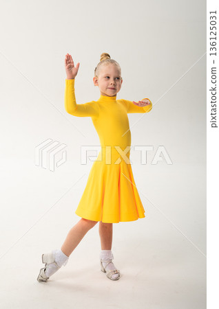 Young girl with cochlear implant performing sport dance in yellow costume on studio background. Hearing loss treatment, auditory rehabilitation, assistive technology, inclusive childhood, and 136125031