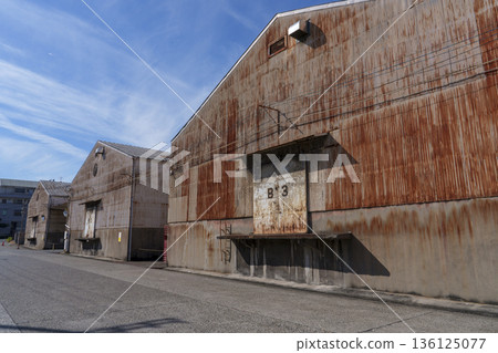 An industrial streetscape lined with rusted factory warehouses An industrial streetscape lined with rusted factory warehouses 136125077