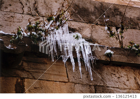 icicles of ice hanging on the facade of a building icicles of ice hanging on the facade of a building 136125413