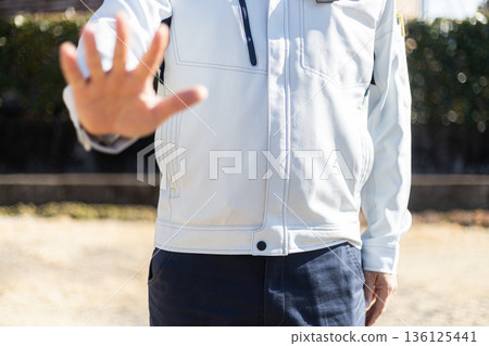 A man in work clothes showing his palm and making a gesture of refusal A man in work clothes showing his palm and making a gesture of refusal 136125441