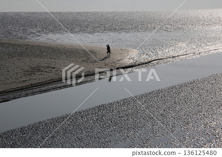 During low tide the water in the river Matla falls so low that people walk to the other shore in Canning Town, India 136125480