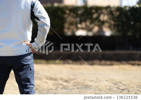 一名身穿工作服的男子背對鏡頭,雙手叉腰站立。 一名身穿工作服的男子背對鏡頭,雙手叉腰站立。 136125536