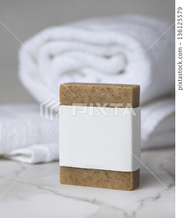 Mockup of brown solid soap bar with blank paper label near white bath towel, personal care packaging Mockup of brown solid soap bar with blank paper label near white bath towel, personal care packaging 136125579
