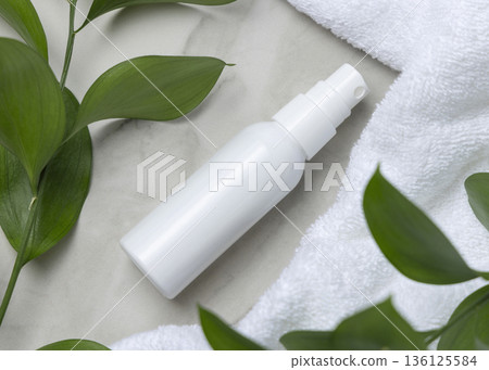 Mockup of blank white spray bottle near white bath terry towel and green leaves. Unbranded cosmetic Mockup of blank white spray bottle near white bath terry towel and green leaves. Unbranded cosmetic 136125584