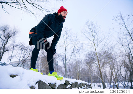 Runner resting hands on knees after winter training outdoors. Runner resting hands on knees after winter training outdoors. 136125634