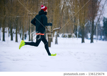 Male runner training in snowy winter park. Male runner training in snowy winter park. 136125674