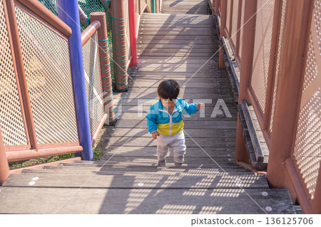 Toddlers running up the stairs of playground equipment in the park 136125706