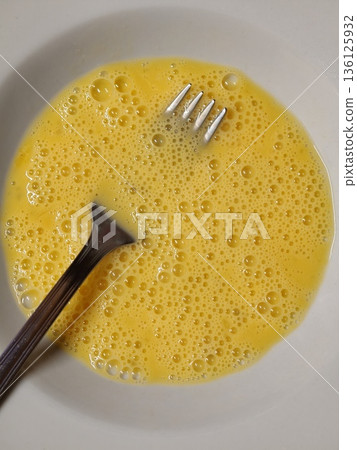 Whisking raw eggs for preparing breakfast ingredients Whisking raw eggs for preparing breakfast ingredients 136125932