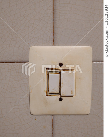 Dirty worn light switch on cracked tile wall Dirty worn light switch on cracked tile wall 136125934