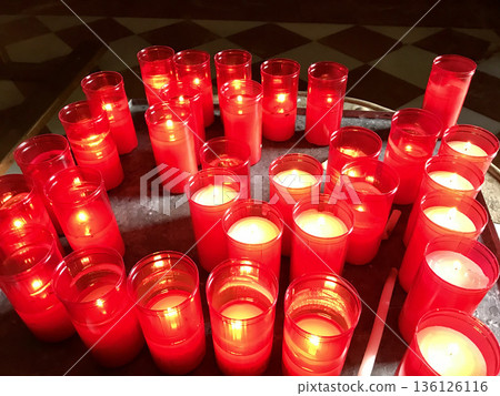 candles lit as an offering at the entrance of a religious temple 136126116