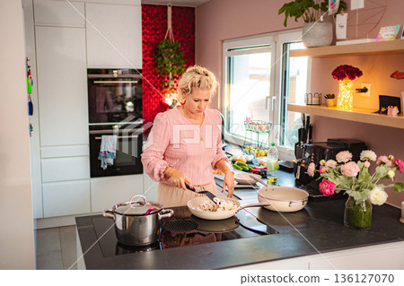 Woman cooking fresh food in a modern kitchen home 136127070