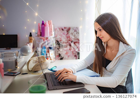 Teenage girl studying on laptop at home desk Teenage girl studying on laptop at home desk 136127074