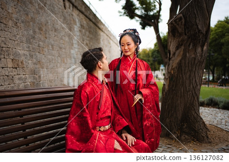 Interracial couple celebrating wedding wearing traditional red Chinese attire Interracial couple celebrating wedding wearing traditional red Chinese attire 136127082