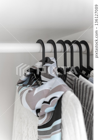 Minimal wardrobe with clothes on hangers in white closet 136127089
