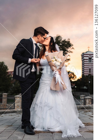 Interracial wedding couple kissing during beautiful sunset 136127099