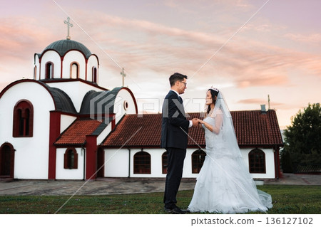 Interracial wedding couple exchanging vows in front of an Orthod Interracial wedding couple exchanging vows in front of an Orthod 136127102
