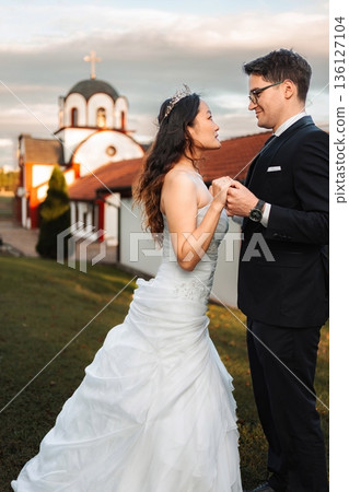 Interracial couple holding hands at wedding outside Orthodox chu 136127104