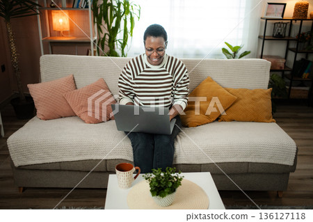 Happy adult woman working from home using laptop Happy adult woman working from home using laptop 136127118