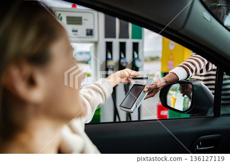 Woman making credit card payment at gas station pump Woman making credit card payment at gas station pump 136127119