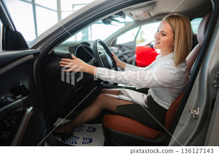 Happy woman test driving new car at dealership 136127143