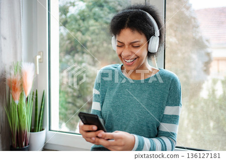 Young black woman laughing listening music using smartphone 136127181