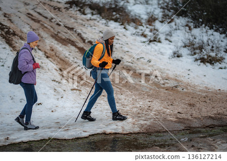 Two women trekking in winter landscape enjoying friendship 136127214