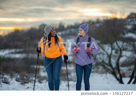 Two women hiking in snow enjoying winter outdoor activity and friendship 136127217