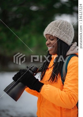 Woman smiling holding binoculars enjoying winter nature Woman smiling holding binoculars enjoying winter nature 136127224