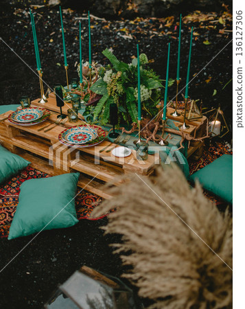 Boho outdoor table setting with plates, gold cutlery and candles on rustic pallets Boho outdoor table setting with plates, gold cutlery and candles on rustic pallets 136127306