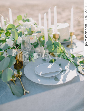 Luxury table centerpiece with candles and floral arrangement in soft sunlight, romantic event styling. 136127310
