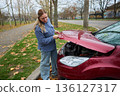 Woman checking car engine in autumn parking lot 136127317