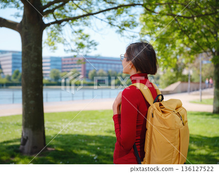 Tourist woman explores modern Frankfurt, walking through vibrant streets with contemporary architecture, skyscrapers, and urban spaces, enjoying lively atmosphere of modern side. Tourist woman explores modern Frankfurt, walking through vibrant streets with contemporary architecture, skyscrapers, and urban spaces, enjoying lively atmosphere of modern side. 136127522