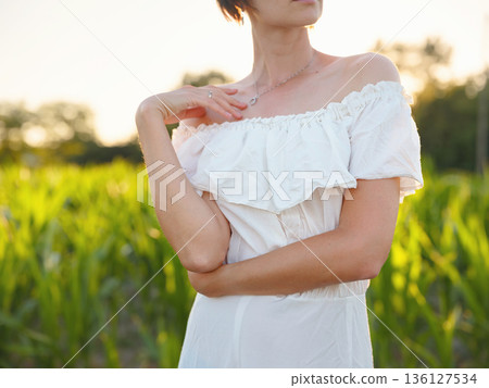 Beautiful woman in white dress standing in summer field during golden sunset in Croatia, warm sunlight, romantic evening mood, natural countryside atmosphere, soft wind and peaceful scene Beautiful woman in white dress standing in summer field during golden sunset in Croatia, warm sunlight, romantic evening mood, natural countryside atmosphere, soft wind and peaceful scene 136127534