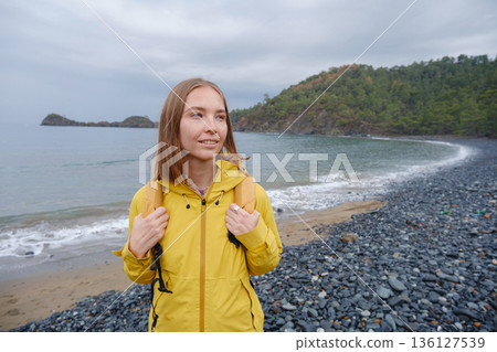 Couple enjoys Turkish coastline. Sitting on stones, watching sea waves, relaxing together, slow romantic moment near calm blue water under soft winter light. 136127539