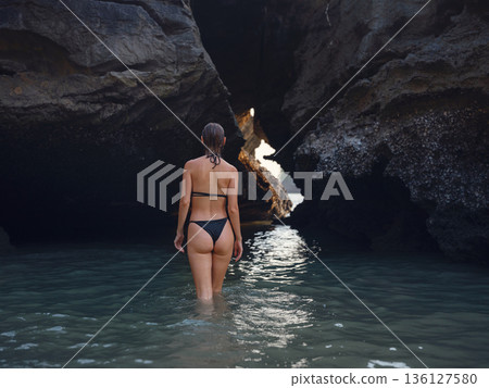 Young woman enjoying serene evening at sea in Krabi, Thailand during sunset. Calm waves, golden light, and peaceful atmosphere highlight tropical beauty and connection with nature. 136127580