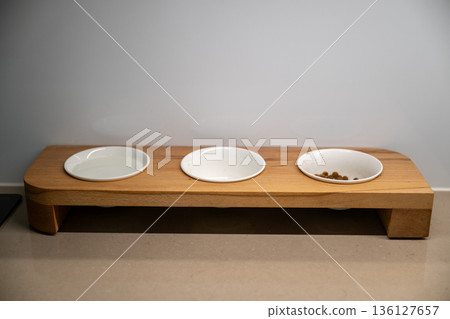 Wooden pet feeder with three bowls on minimalist home background Wooden pet feeder with three bowls on minimalist home background 136127657