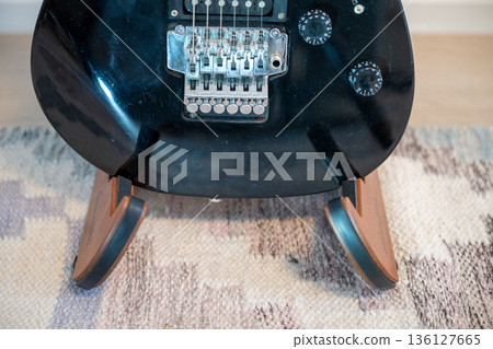 Electric guitar body detail with tremolo bridge on wooden stand Electric guitar body detail with tremolo bridge on wooden stand 136127665