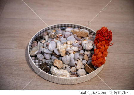 Minimal still life with decorative stones and braided rope on wooden floor 136127683