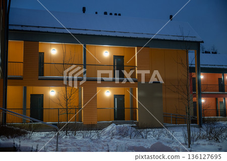 Modern apartment building exterior with warm lights and balconies in winter evening Modern apartment building exterior with warm lights and balconies in winter evening 136127695
