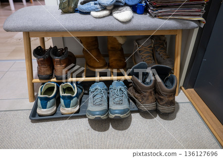 Organized shoe storage bench with winter boots and everyday footwear in cozy home hallway 136127696