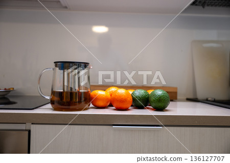 Fresh citrus fruit and glass teapot with hot tea on modern kitchen countertop Fresh citrus fruit and glass teapot with hot tea on modern kitchen countertop 136127707