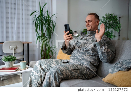 Happy Soldier Video Calling Family While Resting on Sofa at Home Happy Soldier Video Calling Family While Resting on Sofa at Home 136127772