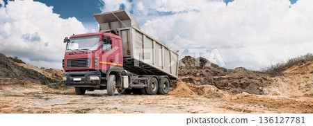 Preparations are underway for excavation work at the construction site. A dump truck is at work, and clouds gather in the blue sky above the landscape Preparations are underway for excavation work at the construction site. A dump truck is at work, and clouds gather in the blue sky above the landscape 136127781