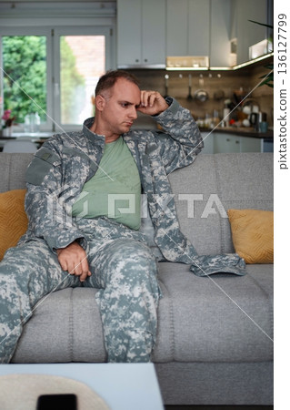 Depressed soldier sitting on sofa at home 136127799