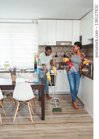 Young couple sweeping and cleaning their kitchen floor Young couple sweeping and cleaning their kitchen floor 136127832