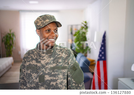 Smiling african american female soldier standing in the living room Smiling african american female soldier standing in the living room 136127880