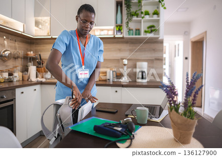 Nurse preparing medical bag in kitchen Nurse preparing medical bag in kitchen 136127900